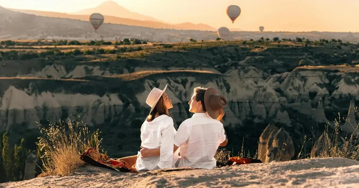 Couple dressed in white infron of hot air balloons.